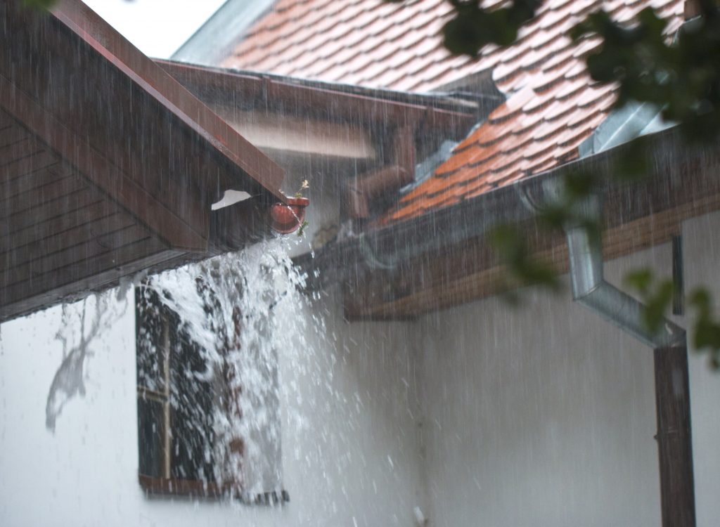 Heavy rain overflowing a roof edge and gutter