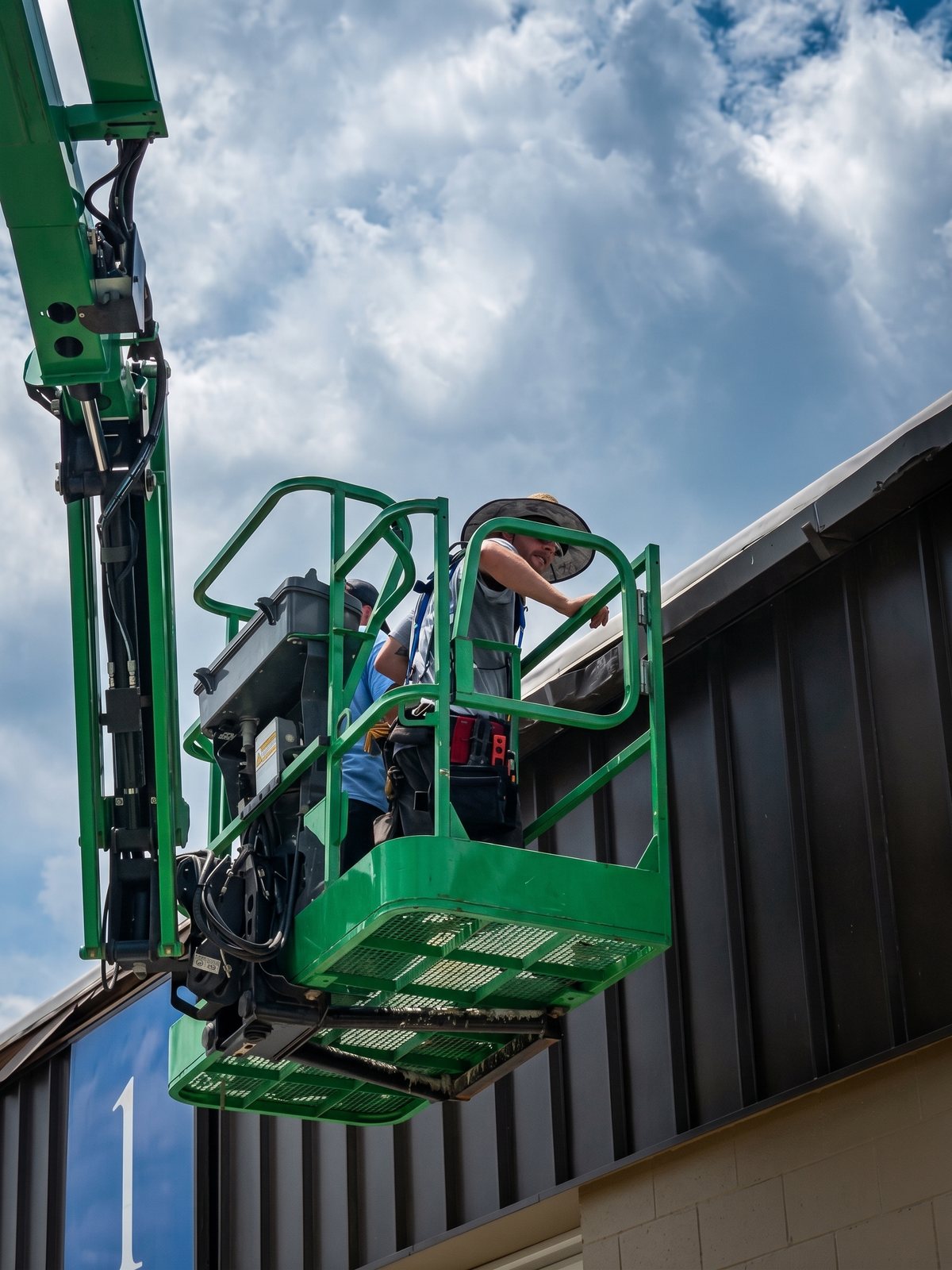 Our crew on a boom lift installing commercial gutters on a metal-roofed building