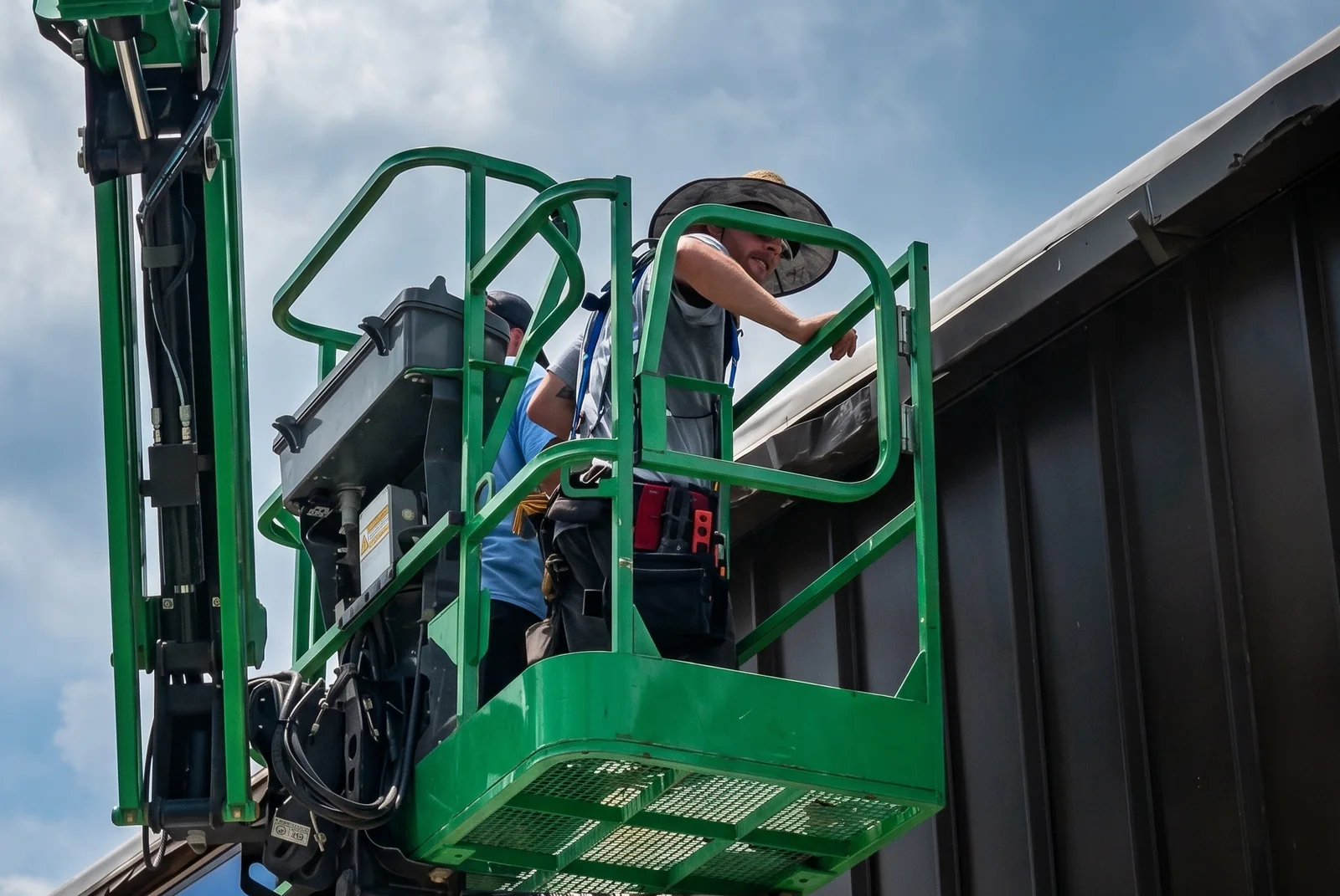 Our crew on a boom lift installing commercial gutters on a metal-roofed building